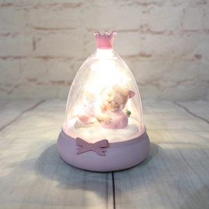 Detail of a crown night light with a sleeping girl figurine on a pink strawberry pillow