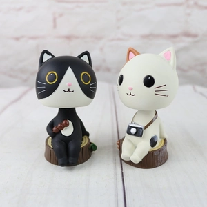 Detail of two resin cartoon cats with camera and snack on a wooden stump base