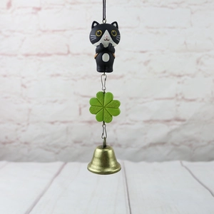 Detail of black and white cat charm with green clover and antique bronze bell pendant