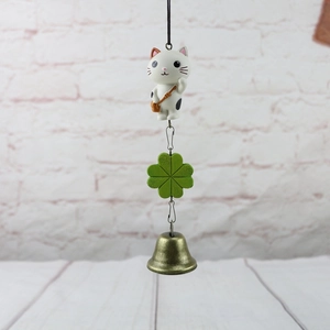 Japanese style cat hanging ornament with green clover and bronze bell on white wall