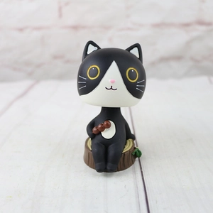Close-up of a cute black and white resin cat figurine with a dango snack on a wood base