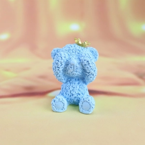 Detail of blue bear cake topper with gold crown and textured surface for car decor