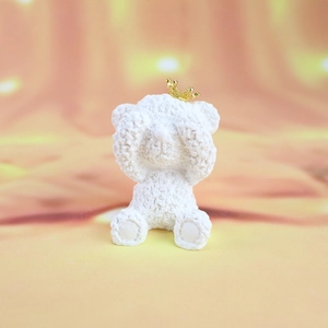 Detailed view of white teddy bear ornament with knitted texture and tiny gold crown