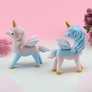 Detail of glittery wings and golden horns on two resin unicorn cake topper figurines