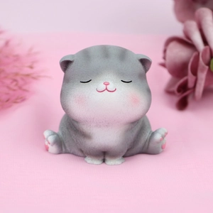 Close-up of cute grey and white resin cat figurine with pink cheeks on pink background