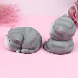 Close-up of grey striped cat figurines with lifelike fur texture and cozy sleeping pose