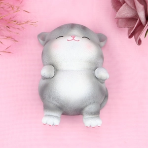 Detailed view of a cute grey and white cat figurine lying on its back with closed eyes