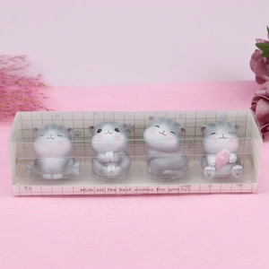 Set of four cute gray and white cat figurines in a transparent gift box on pink fabric