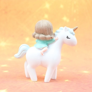 Close-up of a resin unicorn girl cake topper with soft warm bokeh star background
