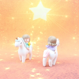 Close-up of cute unicorn cake toppers with stars on dreamlike warm orange background