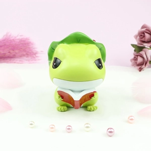 Detail shot of a cute green frog figurine reading a red book with lotus leaf hat decoration