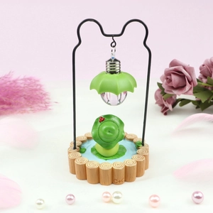 Detail of creative frog night light and piggy bank with miniature lamp and rustic wood fence