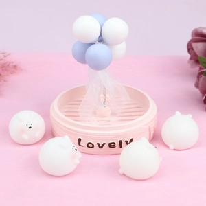 Detail of cute white animal figures in pink steamer base with blue balloons