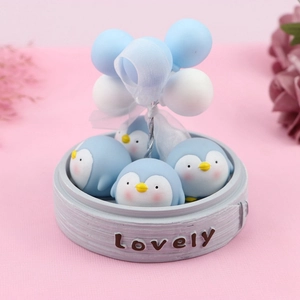 Close-up of cute blue penguin figurines in a wooden tray with balloon cake topper decor