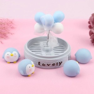 Macro detail of mini penguin figurines with blue balloons on a lovely base decor