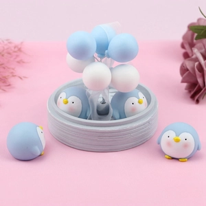 Close-up of cute light blue penguin figurines and balloon cake toppers set