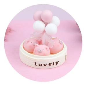 Cute pink pig figurines in a miniature steamer with balloons for car and cake decor