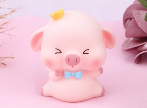 Close-up of pink pig cake topper with golden crown, blue bow, and white wings
