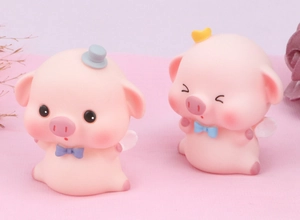 Detail of two cute pink resin pig angel figurines with wings and crowns for cake decoration
