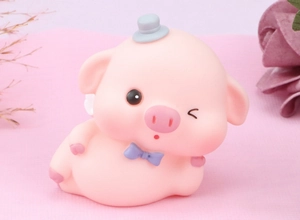 Close-up of cute pink pig figurine with a grey hat and purple bow for cake decoration