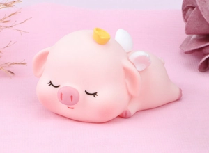 Close-up of cute pink winged pig figurine with golden crown for cake or room decoration