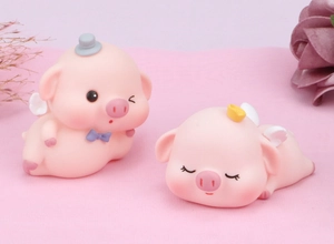 Detail of cute pink pig cake toppers featuring an angel crown and a top hat with bow