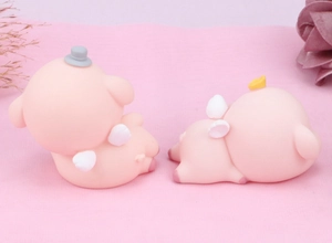 Detail of pink cartoon pig figurines with white wings and crowns on soft pink velvet