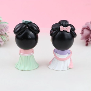 Detail view of the back of two Chinese traditional cartoon princess cake toppers with flowers