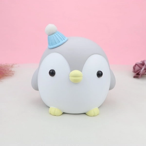 Detalle de luz nocturna de pingüino con gorro azul de punto y textura de silicona suave