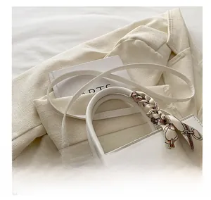 Detail of white leather handbag with silk scarf wrapped handle on cream blazer