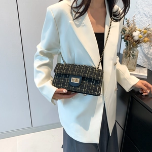 Sac bandoulière en tweed à carreaux avec chaîne dorée présenté sur un blazer blanc