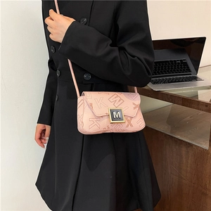 Pink faux leather crossbody bag with letter print and gold M lock on a model in an office