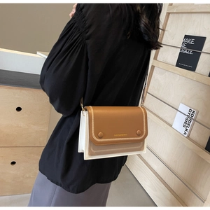 Detail view of contrast color crossbody bag with decorative stitching and round buckles