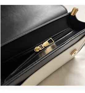 Detail of smooth gold zipper and magnetic closure on contrast shoulder bag interior