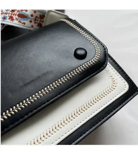 Close-up of litchi-textured contrast crossbody bag with intricate beige stitching