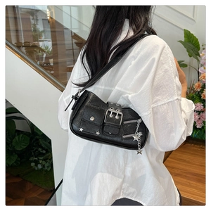 Détail du sac à épaule noir avec rivets et breloques étoiles porté par un mannequin