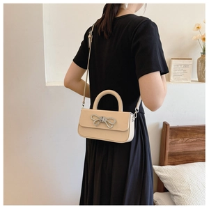 Detail of beige bow-knot crossbody bag with sparkling silver rhinestone buckle decoration