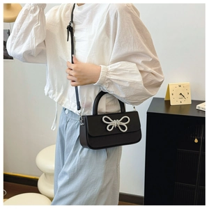 Detailed view of the luxury black crossbody bag featuring a sparkling crystal bow decoration