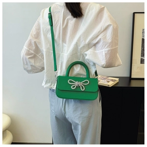 Detail of green bow shoulder bag showing rhinestone butterfly knot on a stylish model