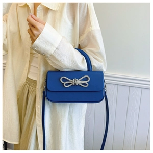 Detail view of the silver rhinestone bow on the blue leather flap crossbody handbag