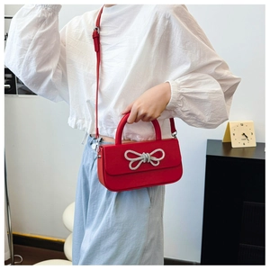 Detail of red crossbody bag with silver rhinestone bow on elegant rectangle flap