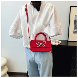 Detail of red crossbody bag with silver crystal bow on model for size perspective