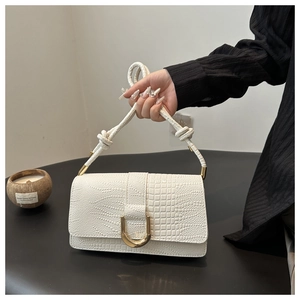 Détail du sac blanc gaufré crocodile avec fermoir doré et bandoulière en nœud tissé