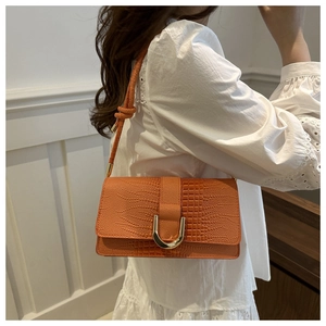 Détail du sac orange gaufré crocodile avec boucle en U dorée et bandoulière à nœud décoratif