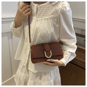 Détail du sac en cuir gaufré crocodile marron foncé avec boucle en U dorée sur modèle