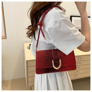 Détail du sac bandoulière rouge effet crocodile avec une boucle en métal fer à cheval