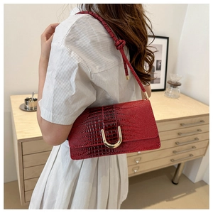 Détail du sac à main rouge motif crocodile avec boucle dorée et bandoulière nouée