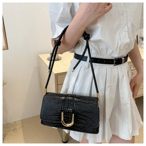 Vue latérale d'un sac à bandoulière noir motif crocodile avec boucle en U dorée