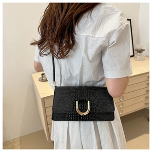 Détail du sac à bandoulière en similicuir crocodile noir avec boucle dorée en forme de U