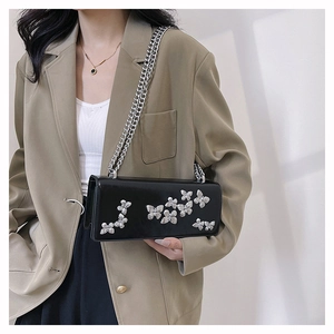 Detailed close-up of glossy black crossbody bag with silver butterfly metal embellishments